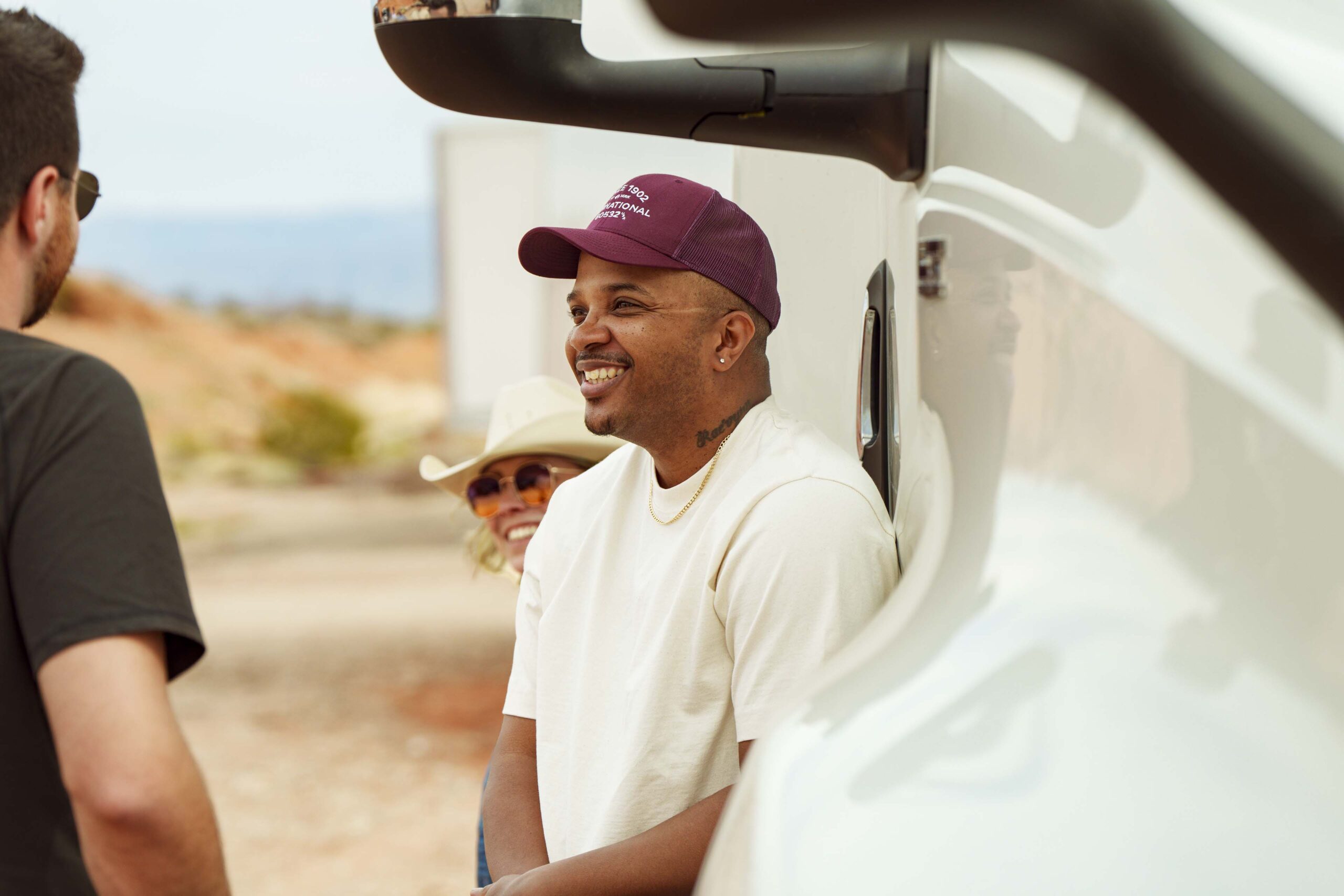 Three truck drivers converse while standing next to an International LT model truck
